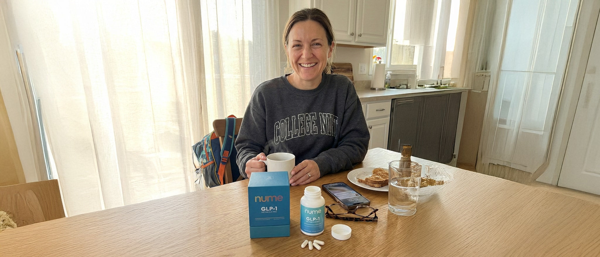 Woman at kitchen table with Nume GLP-1 supplements during morning routine