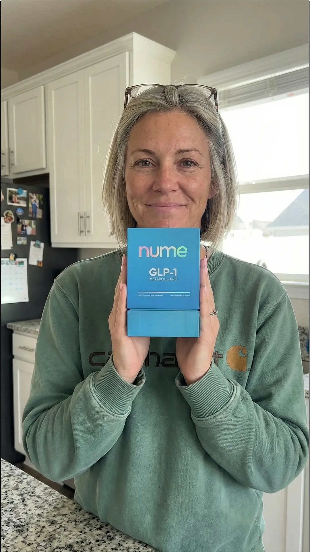 Woman in kitchen holding Nume GLP-1 Metabolic Pro box